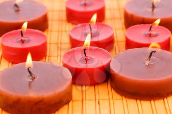 Many candles on bamboo mat background.