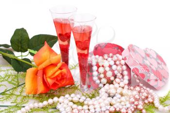 Two glasses, rose, colorful pearls necklaces and gift box on white background.