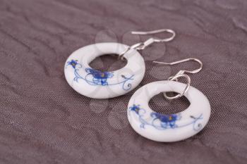 Ceramic earrings on fabric background.