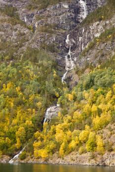 Waterfall and forest with colorful trees in Norway.