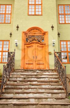 Old buiding entrance with metallic handrails and wooden door in Oslo, Norway.