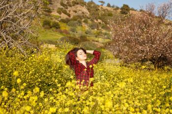 Young pretty woman in yellow daisy flowers field.