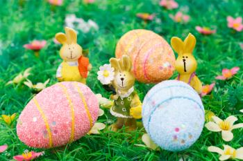 Easter bunny and egg candles on artificial grass background.