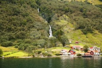 Landscape with Naeroyfjord, waterfall, mountains and traditional village houses in Norway.