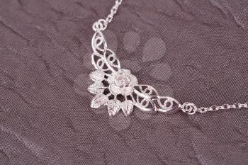 Silver necklace on fabric background.