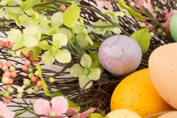 Easter colorful eggs in nest and flowers.