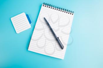 Notepads and pen on a blue background.