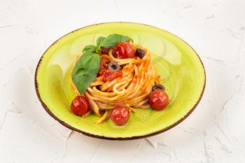 Pasta spaghetti Napoli or Napolitana on green plate on gray background. Italian cuisine.