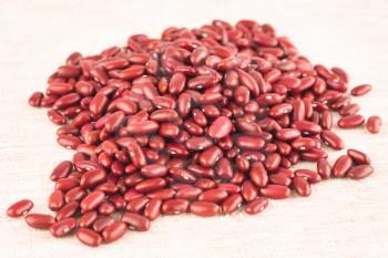 The heap of the red kidney beans on the fabric background, close up picture.