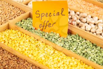 The collection of different groats, peas, wheat, buckwheat and chickpeas in the wooden box with notice special offer.