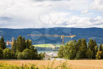 Landscape with mountains, river and construction crane in Lillehammer, Norway.