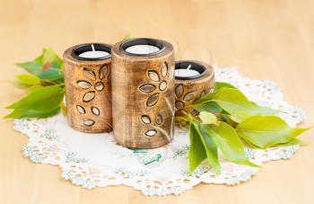 Three brown ancient style candle nests and green leaves on cloth.
