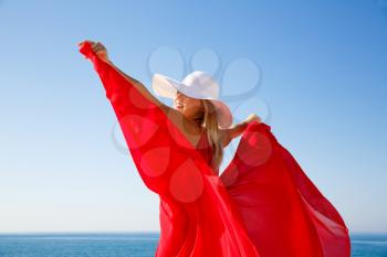 Blond woman in the red dress with the white hat at the beach in Cyprus.