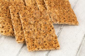 Pile of crackers with spices on gray wooden background.