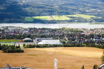 Landscape with wheat field, river and houses in Norwegian Lillehammer town.
