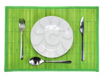 Table serving-knife,plate,fork on  green colour background.