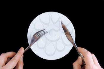 Table serving-knife, fork in hands on colour background.