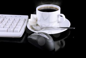Cup of coffee, part of keyboard,mouse on a black background.