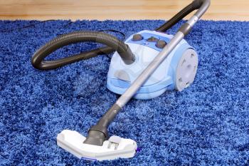 Powerful vacuum cleaner stand  on blue carpet.
