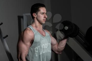 young bodybuilder doing heavy weight exercise for biceps with dumbbell