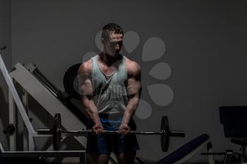 young bodybuilder doing heavy weight exercise for biceps with barbell