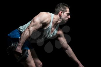 young bodybuilder doing heavy weight exercise for back on black background