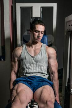 bodybuilder doing heavy weight exercise for legs on machine leg extensions