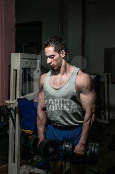bodybuilder doing heavy weight exercise for shoulder white dumbbell