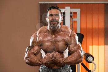 Bodybuilder Standing In The Gym And Flexing Muscles