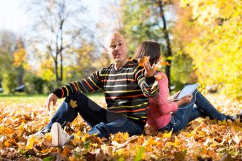 Couple Listening To Music And Throwing Leaves
