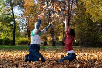 Couple Having Fun With Autumn Leaves In Garden