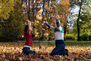 Couple Throwing Leaves In The Air