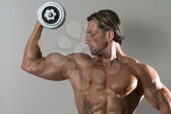 Mature Man Working Out Biceps - Dumbbell Concentration Curls On Grey Background