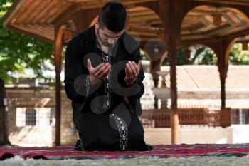 Young Muslim Man Making Traditional Prayer To God While Wearing A Traditional Cap Dishdasha