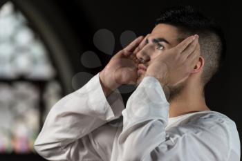 Young Muslim Man Making Traditional Prayer To God While Wearing A Traditional Cap Dishdasha