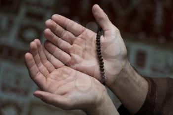 Close-Up Of Male Hands Praying With Rosary