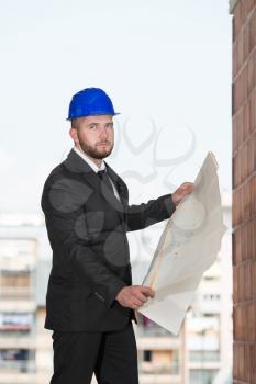 Portrait Of Construction Master With Blue Helmet And Blueprint In Hands