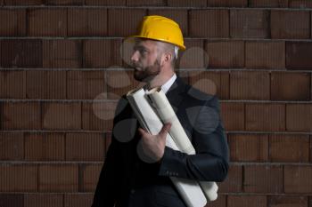 Portrait Of Construction Master With Yellow Helmet And Blueprint In Hands