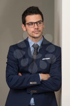 Portrait Of Handsome Confident Young Businessman Standing Arms Crossed