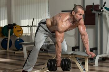 Healthy Man Doing Back Exercises In The Gym With Dumbbell