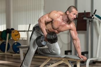 Healthy Man Doing Back Exercises In The Gym With Dumbbell
