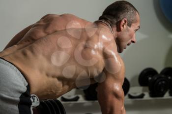 Healthy Man Doing Back Exercises In The Gym With Dumbbell