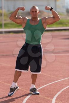 Bodybuilder Performing Front Double Biceps Poses At Tennis Place