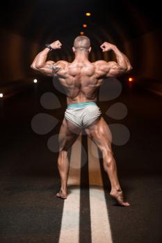 Bodybuilder Performing Rear Double Biceps Poses In Tunnel