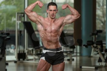 Serious Men Standing In The Gym And Flexing Muscles