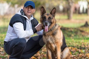 Man Playing With Dog German Shepherd In Park