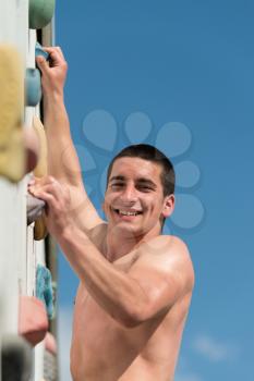 Young Man Climbs Up An Outdoors Rock Wall - He Is Clearly Determined To Make It To The Top