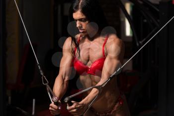 Young Woman In Underwear Is Working On Her Chest With Cable Crossover In A Dark Gym