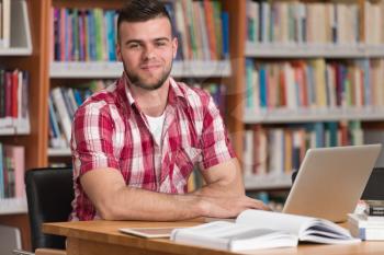 In The Library - Handsome Male Student With Laptop And Books Working In A High School - University Library - Shallow Depth Of Field