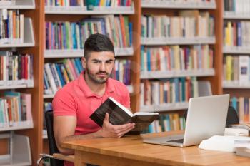 In The Library - Handsome Arabic Male Student With Laptop And Books Working In A High School - University Library - Shallow Depth Of Field